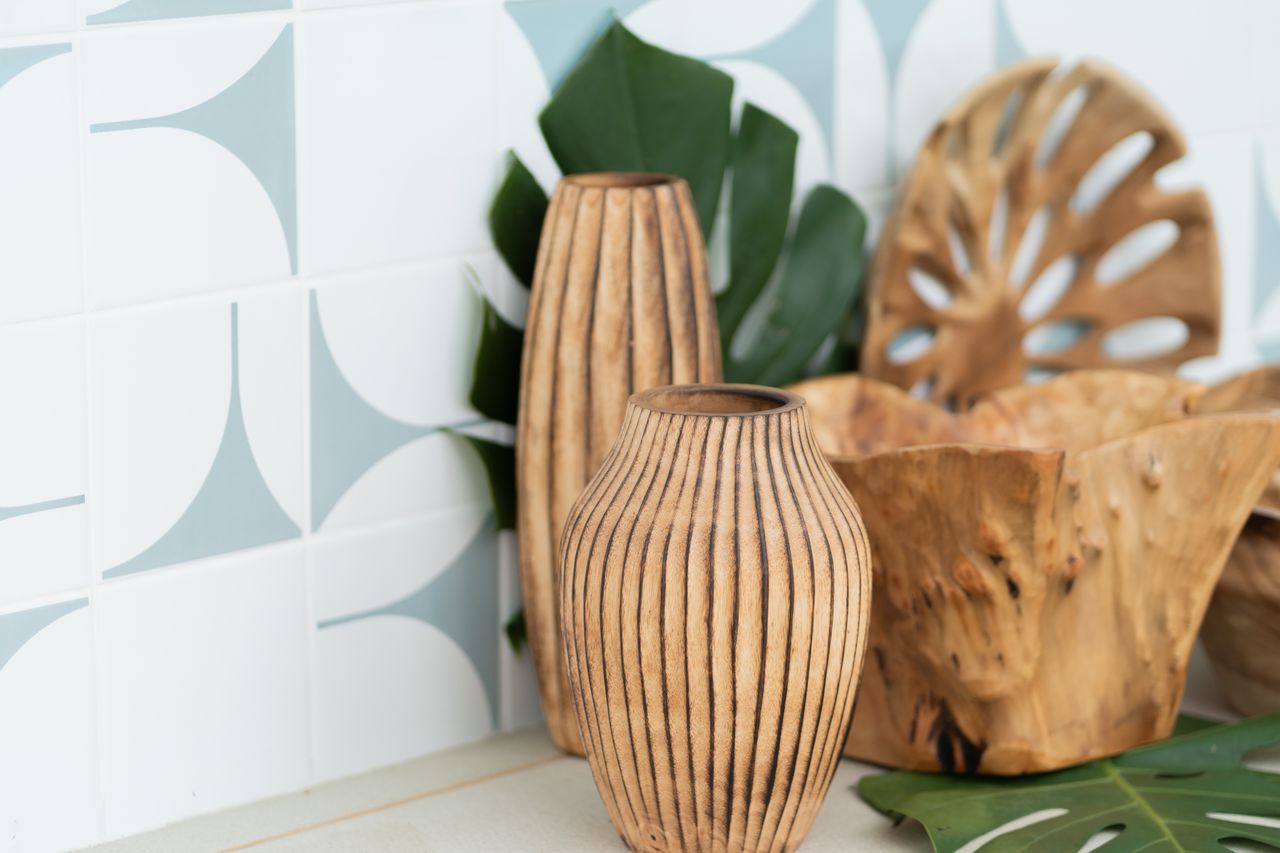 Wooden vases and bowls with monstera leaves for a rustic and natural decor theme.